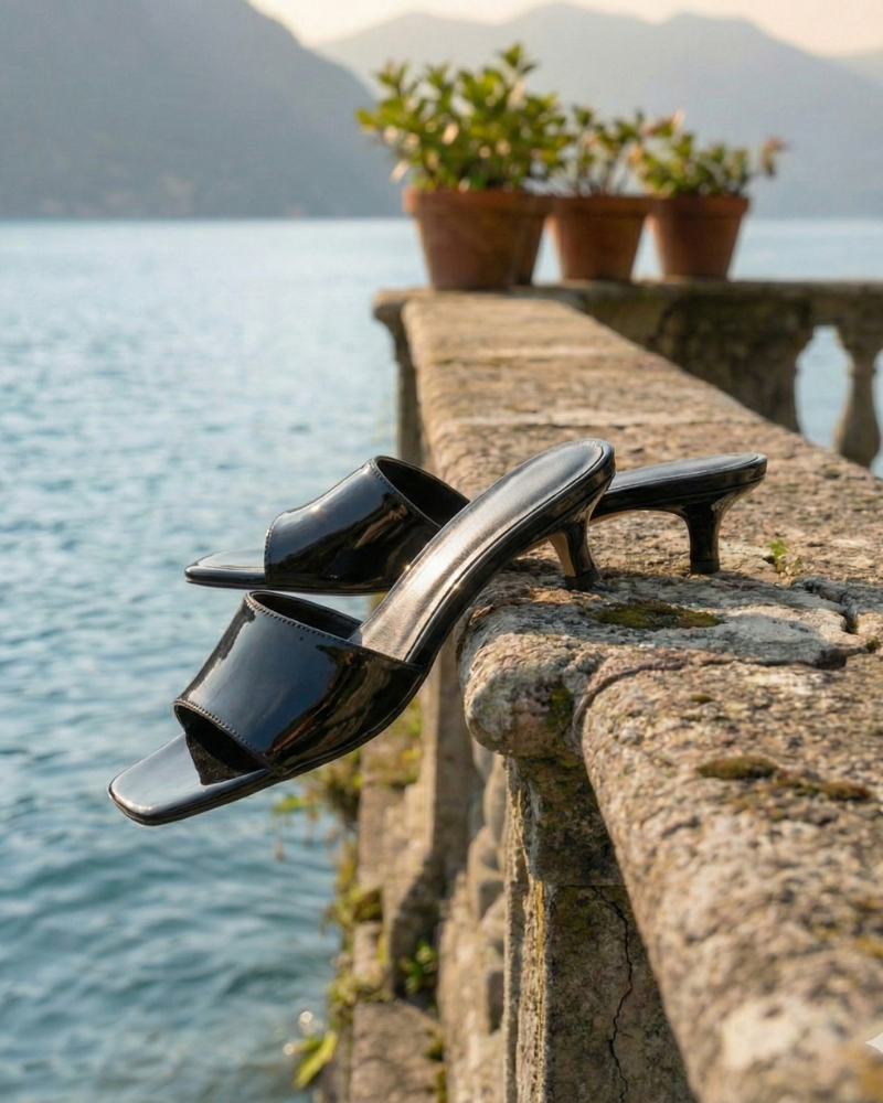black kitten heel sandals placed on stone railing near water